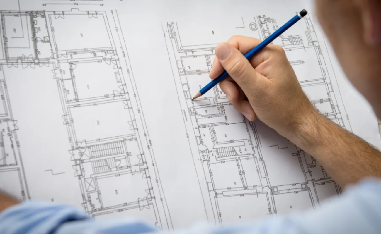 Architect sketching over floor plan drawings